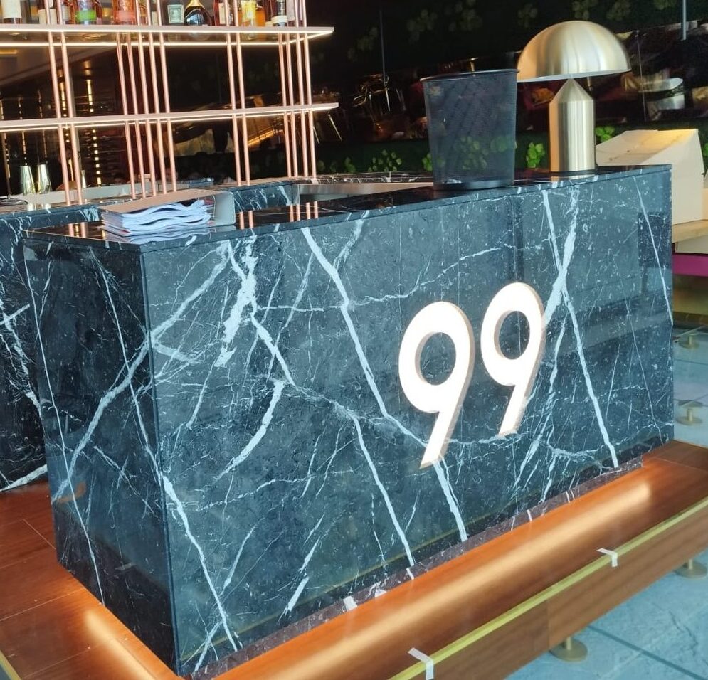 Banque d’accueil sur mesure en marbre Noir Marquina avec éclairage intégré dans un restaurant haut de gamme à Monaco.
