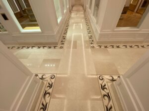 Couloir du Château de La Messardière habillé de pierre naturelle claire avec marqueteries décoratives réalisées sur mesure.