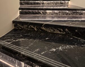 Escalier habillé de marbre Nero Marquina noir veiné de blanc, avec éclairage LED intégré soulignant chaque marche.