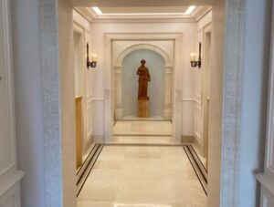 Hall d’entrée avec encadrements architecturaux en pierre naturelle, sols raffinés et perspective majestueuse mettant en valeur une niche décorative.