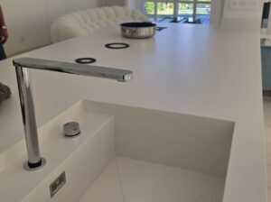 Îlot central en Dekton blanc avec évier intégré, plaque de cuisson Gaggenau sous plan et finitions haut de gamme.