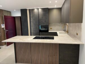 Cuisine contemporaine avec îlot central, plan de travail et crédence en quartzite Taj Mahal aux nuances beige ivoire.