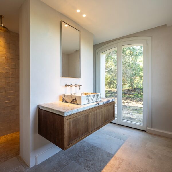 Salle de bains élégante avec vasque à poser et plan de toilette en marbre Calacatta Viola, réalisée sur mesure dans une villa haut de gamme.