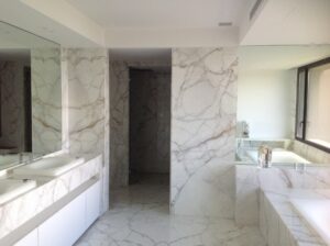 Salle de bains contemporaine habillée de Calacatta, avec double vasque suspendue, baignoire intégrée et revêtements assortis du sol aux murs.