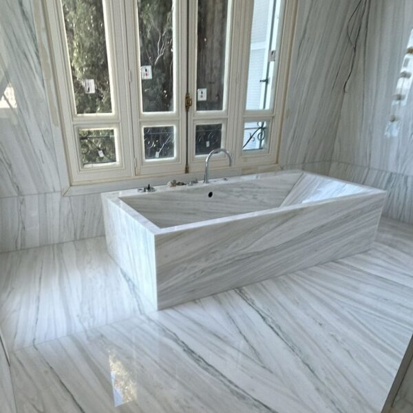 Salle de bains de luxe entièrement réalisée en marbre White Macaubas avec baignoire monolithique, revêtements muraux et sol en pierre naturelle.