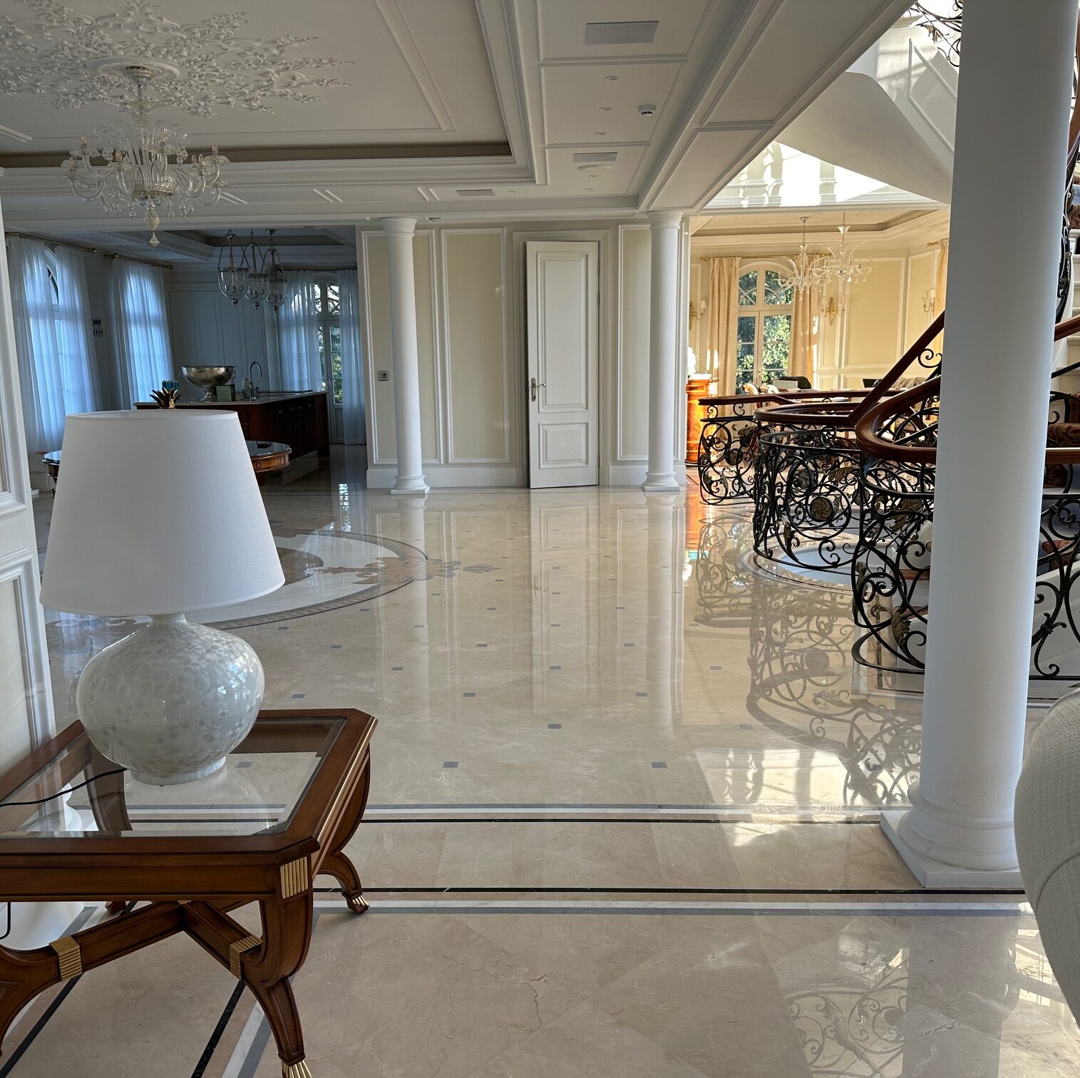 Sol en marbre Crema Marfil poli avec frises décoratives noires dans le hall d'entrée d'une villa de luxe à l'architecture classique.